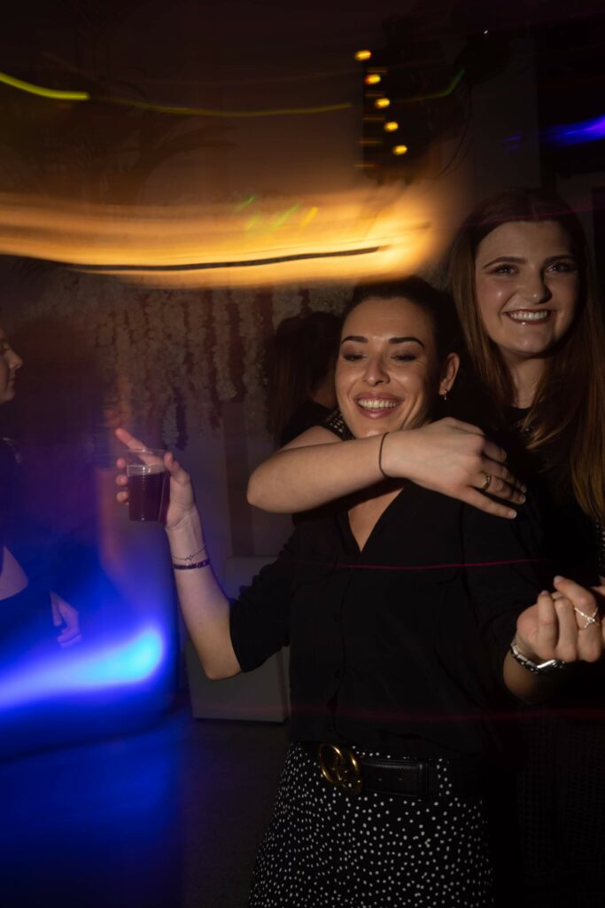 Photo de deux jeunes femmes qui dansent dans un mariage éclairé avec un effet flash